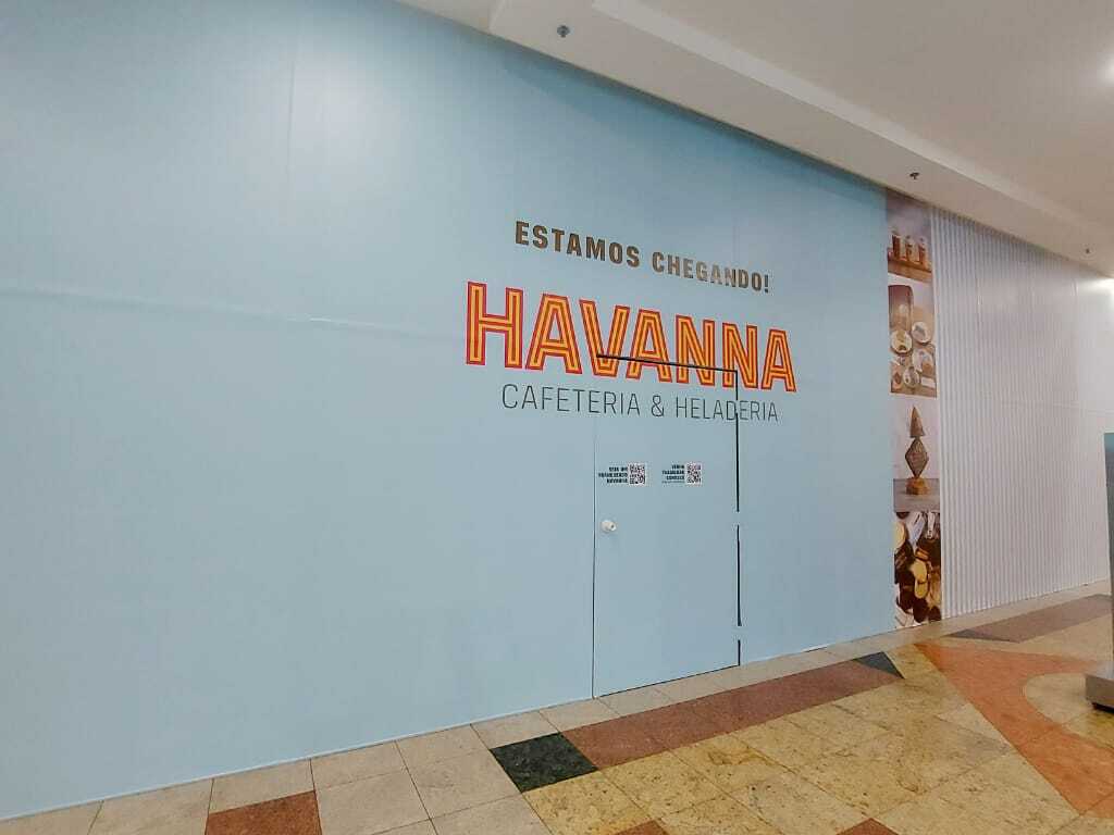Parede com aviso de inauguração da unidade Havanna Cafeteria & Heladeria em shopping, com a frase "Estamos chegando!" destacada.